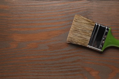 Photo of Applying walnut wood stain. Brush on wooden surface, top view. Space for text