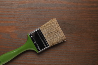 Photo of Applying walnut wood stain. Brush on wooden surface, top view