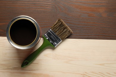 Photo of Applying walnut wood stain. Brush and can on wooden surface, flat lay. Space for text