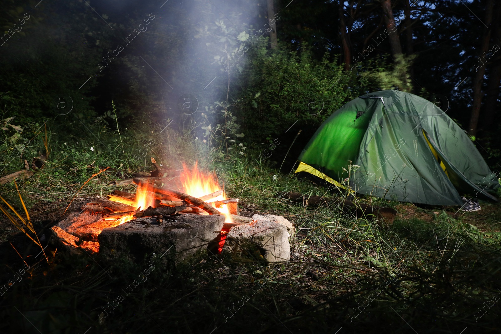 Photo of Bonfire and camping tent in forest at night