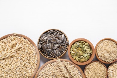 Photo of Different types of cereals and seeds on white wooden table, flat lay. Space for text