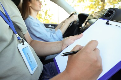 Photo of Driving school. Student passing driving test with examiner in car, closeup