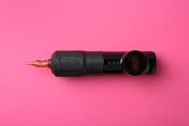 Photo of Professional permanent makeup machine with power supply on pink background, top view