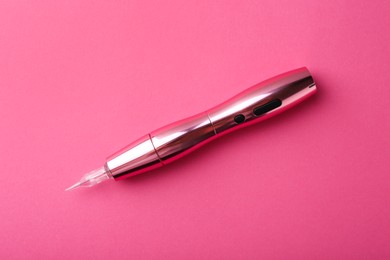 Professional permanent makeup machine on pink background, top view