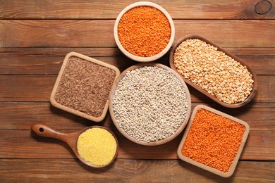 Photo of Different types of cereals and legumes on wooden table, flat lay