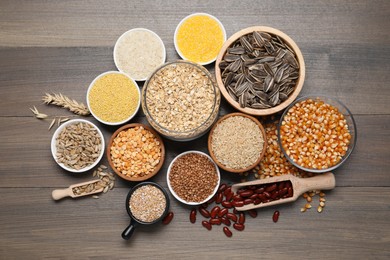 Photo of Different types of cereals, seeds and legumes on wooden table, flat lay