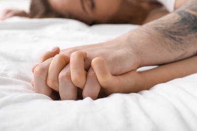 Photo of Lovely couple holding hands in bed, closeup