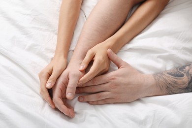 Photo of Lovely couple holding hands in bed, top view