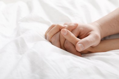 Photo of Lovely couple holding hands in bed, closeup. Space for text