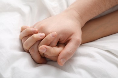 Photo of Lovely couple holding hands in bed, closeup