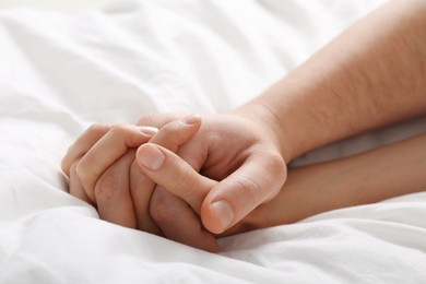 Photo of Lovely couple holding hands in bed, closeup