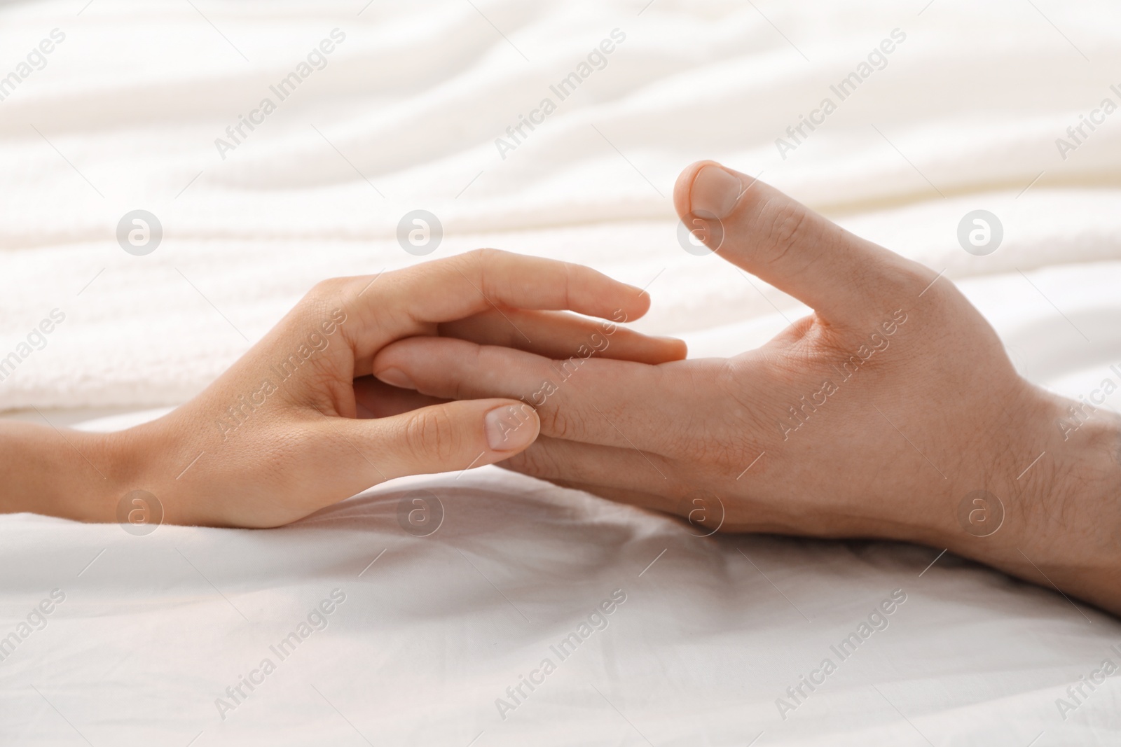 Photo of Lovely couple holding hands in bed, closeup