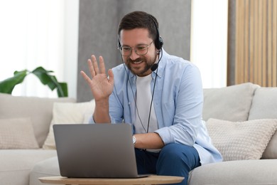 Interpreter in headset having video chat via laptop at wooden table indoors