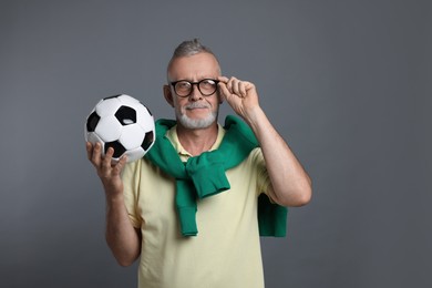 Portrait of handsome senior man with soccer ball on grey background