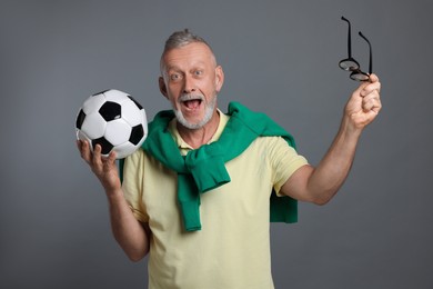 Photo of Portrait of emotional senior man with soccer ball on grey background