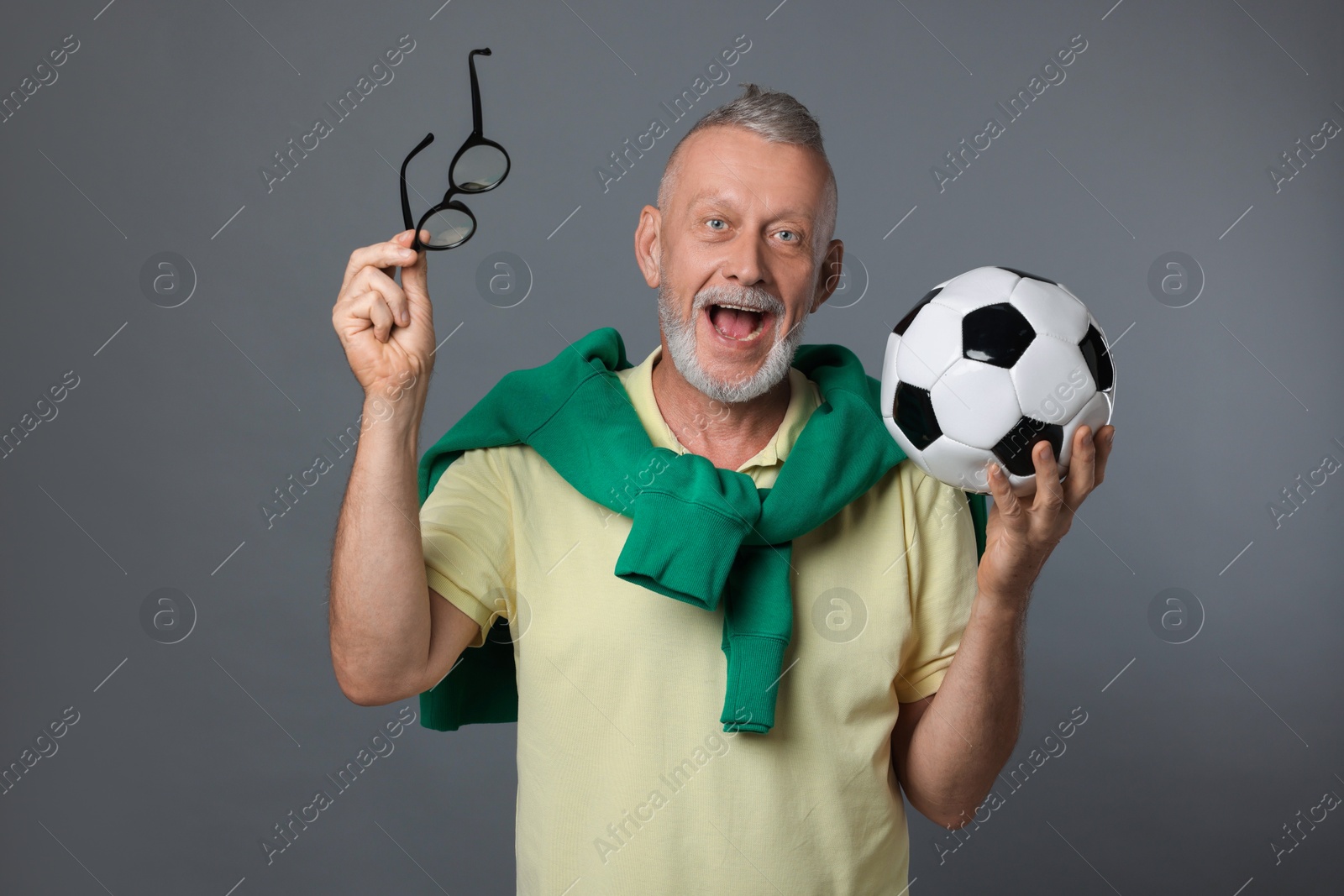 Photo of Portrait of emotional senior man with soccer ball on grey background