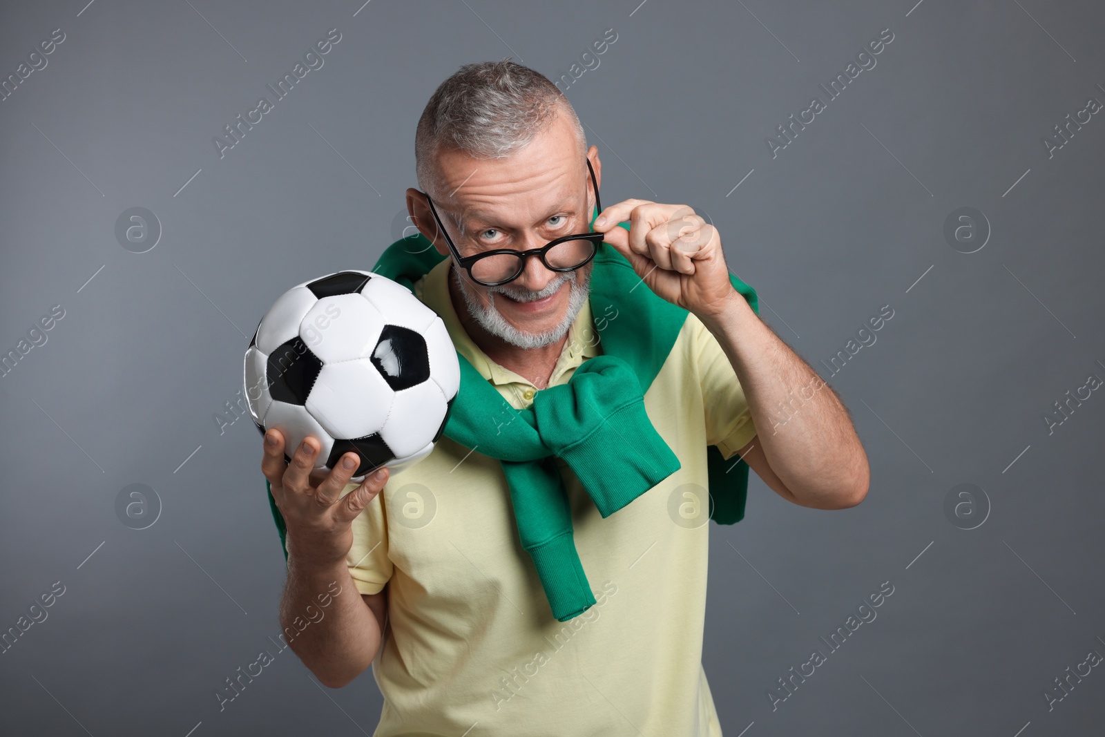 Photo of Portrait of handsome senior man with soccer ball on grey background