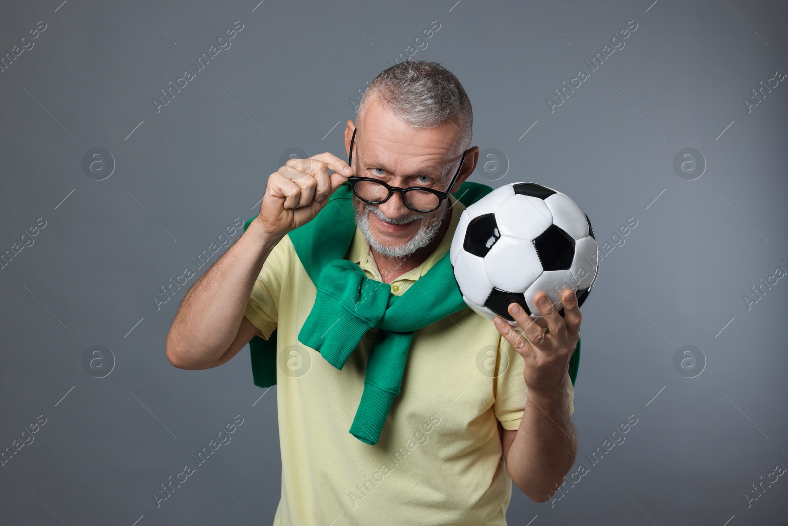 Photo of Portrait of handsome senior man with soccer ball on grey background