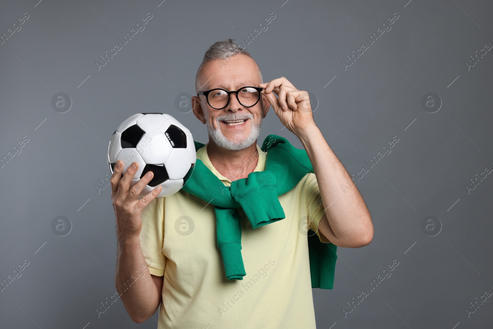 Photo of Portrait of happy senior man with soccer ball on grey background