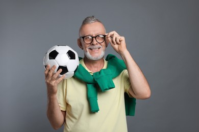 Photo of Portrait of happy senior man with soccer ball on grey background