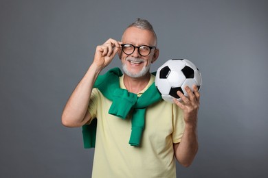 Photo of Portrait of happy senior man with soccer ball on grey background