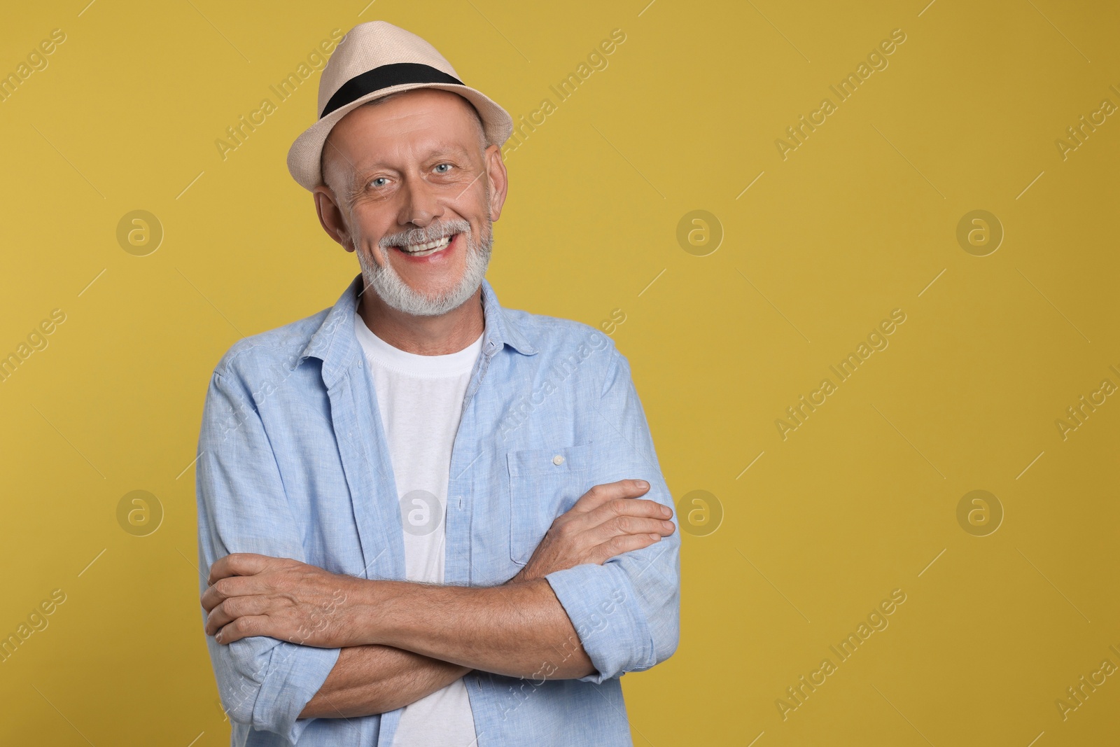 Photo of Portrait of happy senior man with crossed arms on yellow background. Space for text