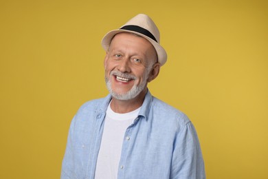 Portrait of happy senior man on yellow background