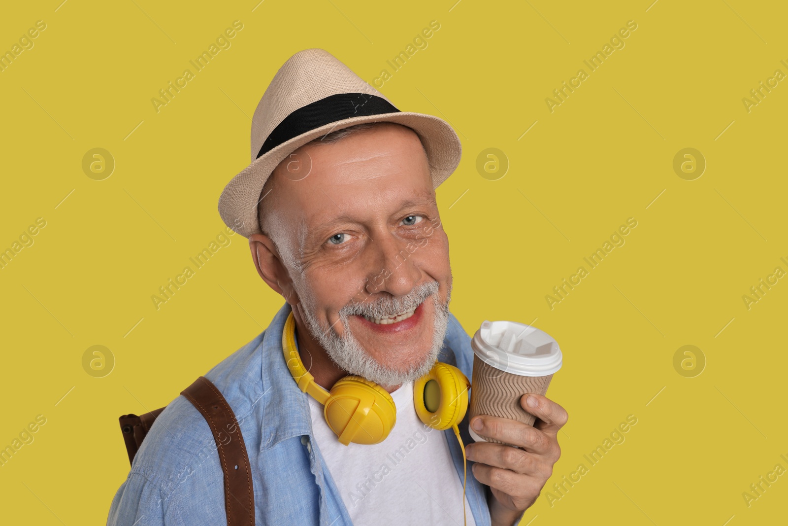 Photo of Portrait of happy senior man with paper cup on yellow background