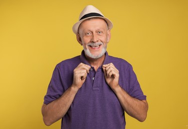 Portrait of happy senior man on yellow background