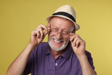 Portrait of happy senior man on yellow background