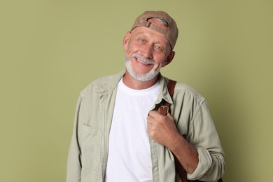 Portrait of happy senior man with backpack on green background