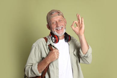 Portrait of happy senior man showing ok gesture on green background