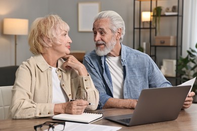 Photo of Pension savings. Senior couple planning budget at wooden table indoors