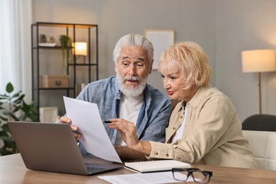 Photo of Pension savings. Senior couple planning budget at wooden table indoors