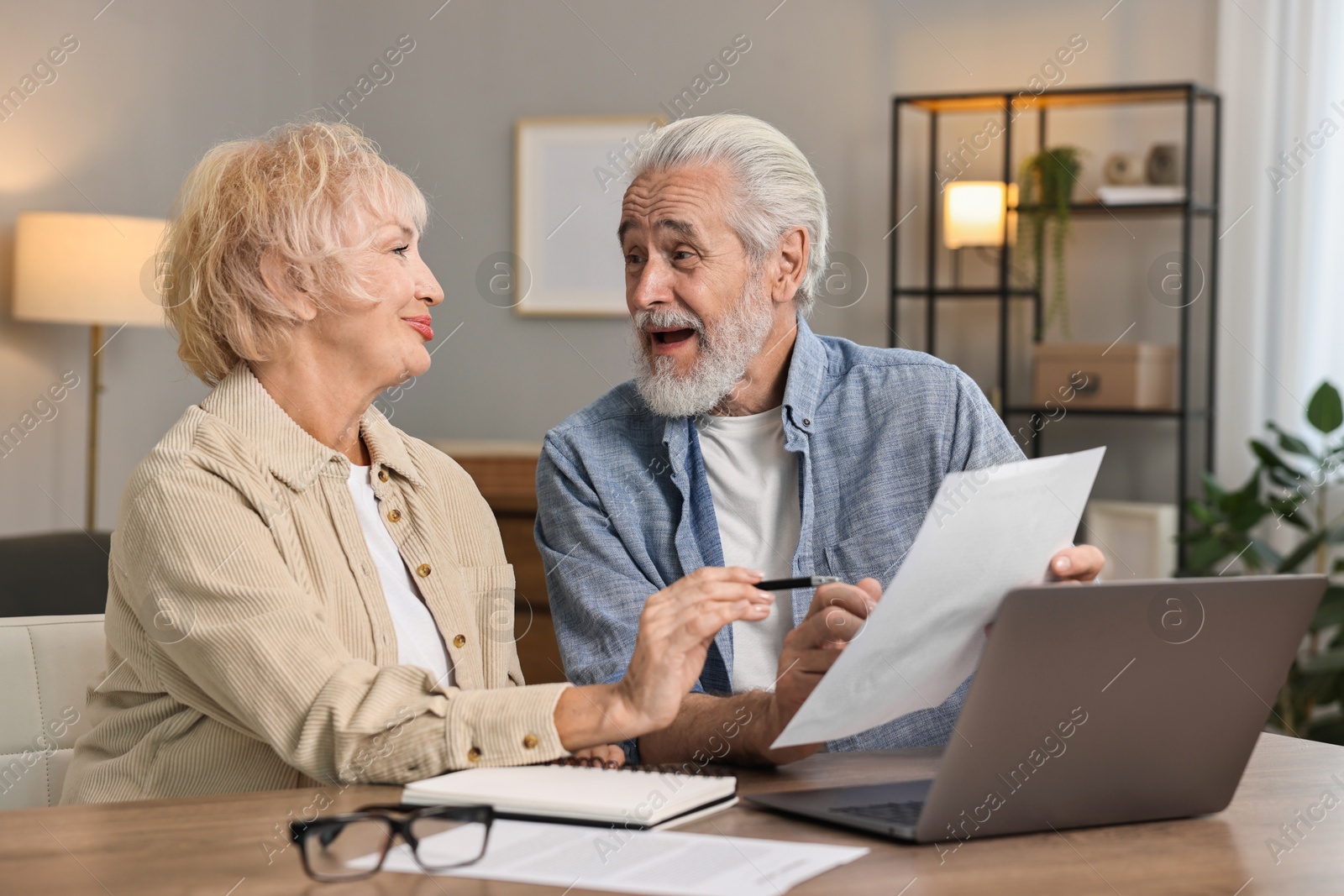 Photo of Pension savings. Senior couple planning budget at wooden table indoors