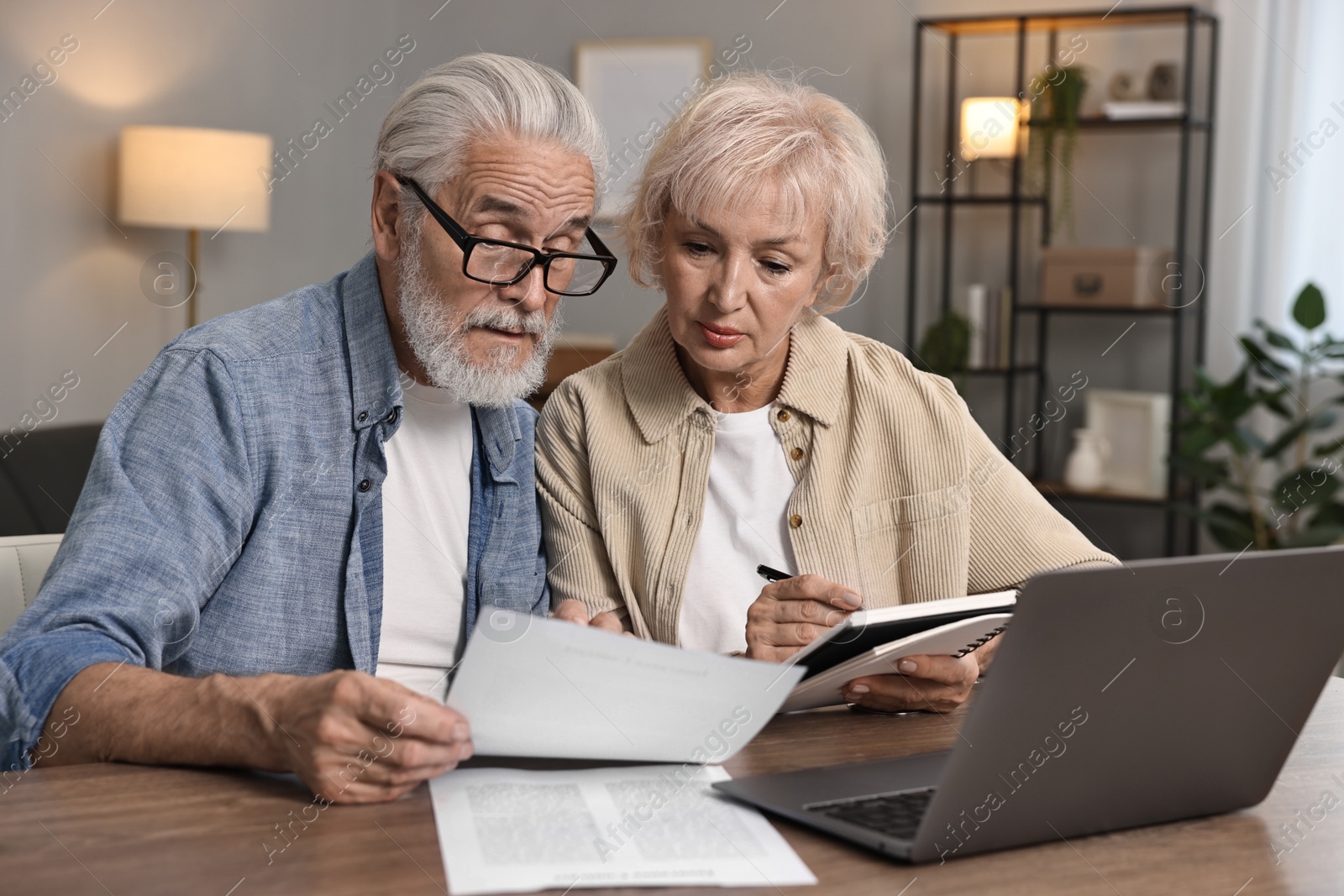 Photo of Pension savings. Senior couple planning budget at wooden table indoors