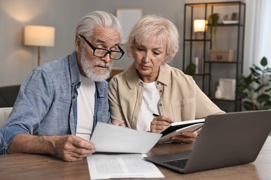 Photo of Pension savings. Senior couple planning budget at wooden table indoors