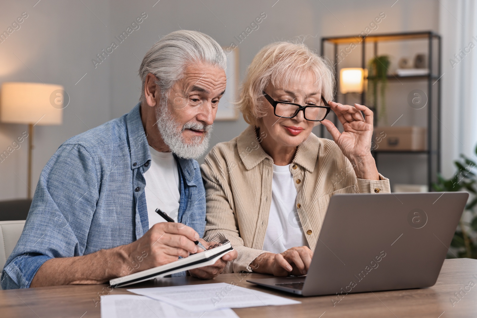 Photo of Pension savings. Senior couple planning budget at wooden table indoors