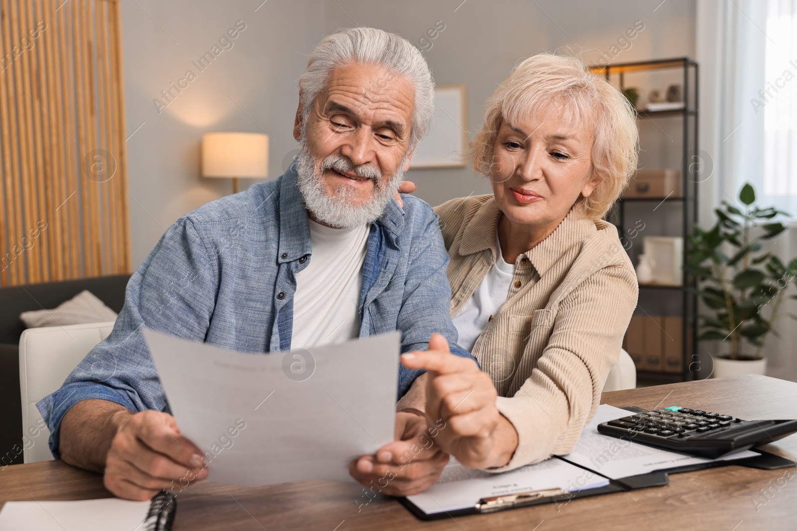 Photo of Pension savings. Senior couple planning budget at wooden table indoors