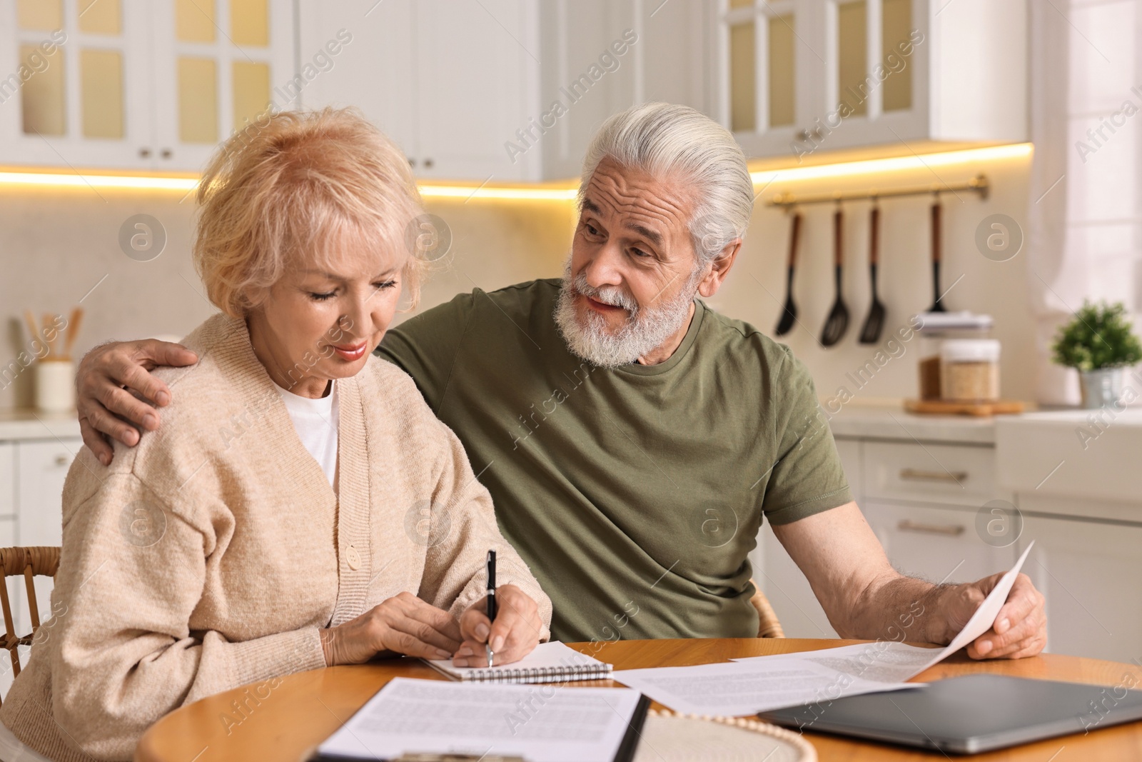 Photo of Pension savings. Senior couple planning budget at wooden table indoors