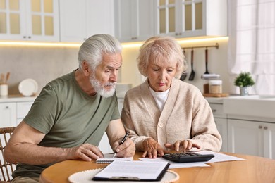 Pension savings. Senior couple planning budget at wooden table indoors