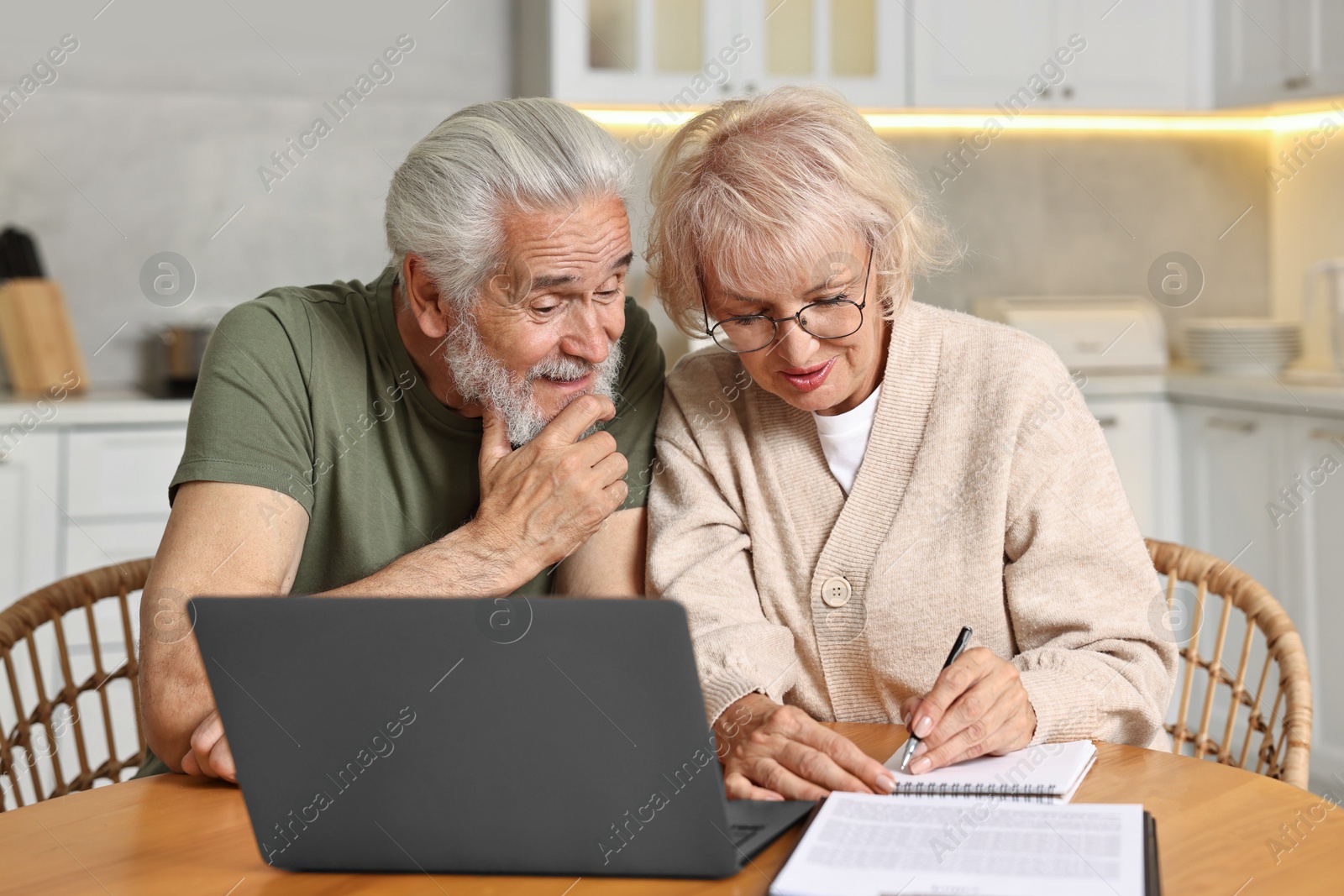 Photo of Pension savings. Senior couple planning budget at wooden table indoors