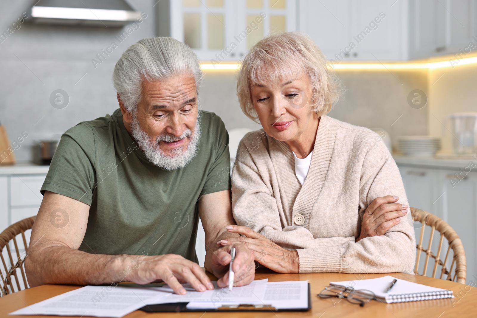 Photo of Pension savings. Senior couple planning budget at wooden table indoors