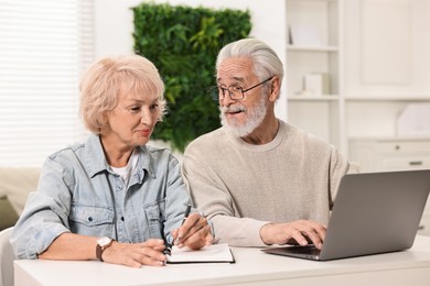 Photo of Pension savings. Senior couple planning budget at white table indoors