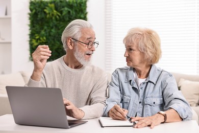 Pension savings. Senior couple planning budget at white table indoors