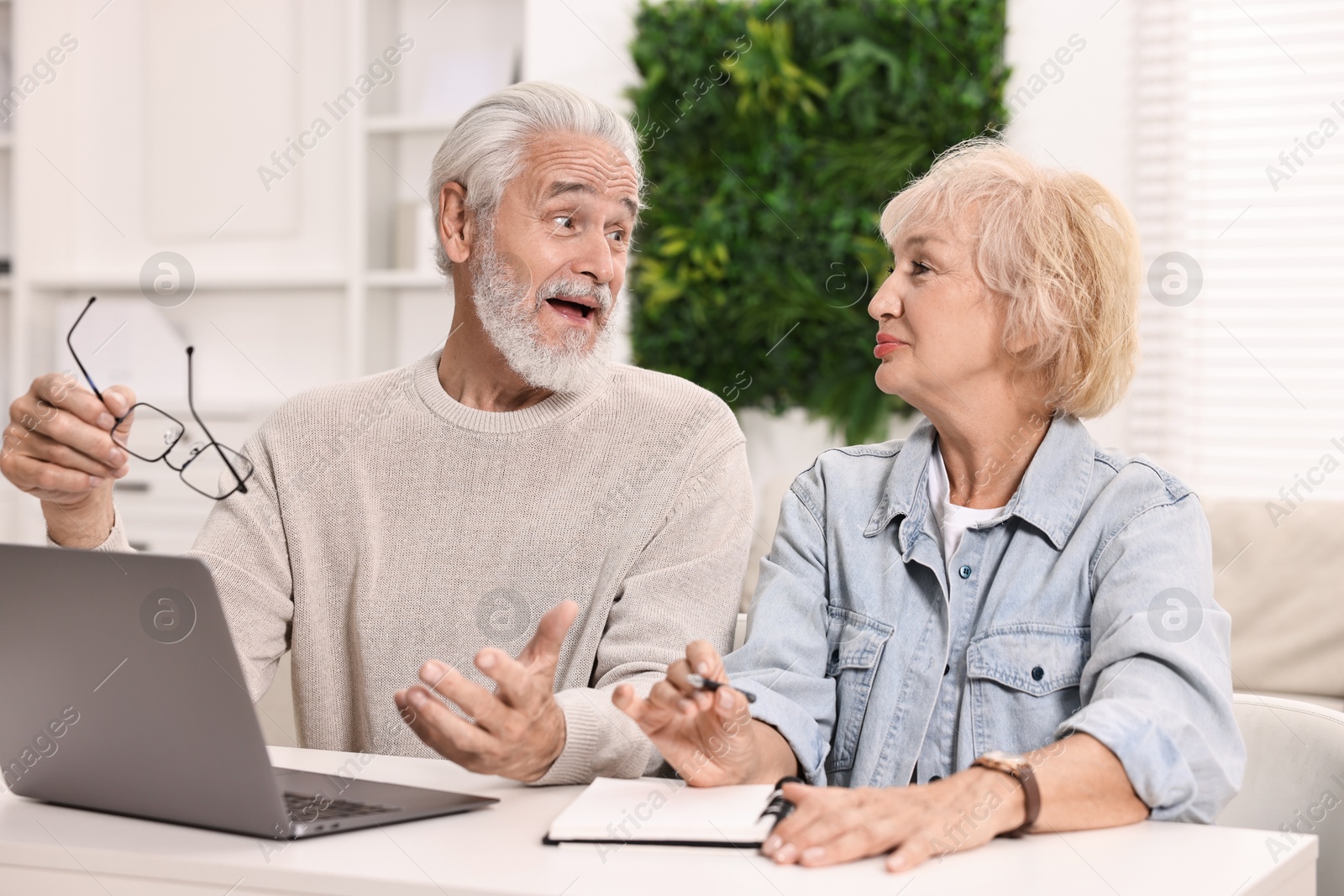 Photo of Pension savings. Senior couple planning budget at white table indoors