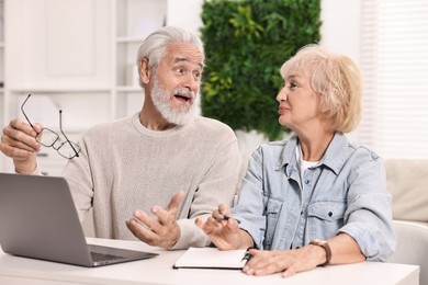 Pension savings. Senior couple planning budget at white table indoors