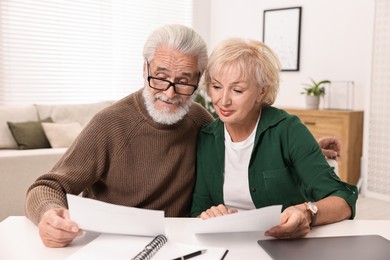 Photo of Pension savings. Senior couple planning budget at white table indoors