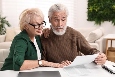 Pension savings. Senior couple planning budget at white table indoors