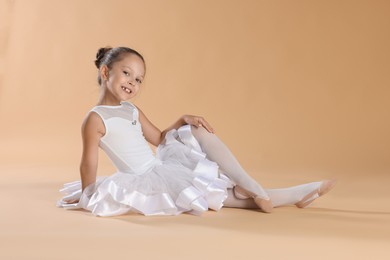 Portrait of little ballerina on beige background